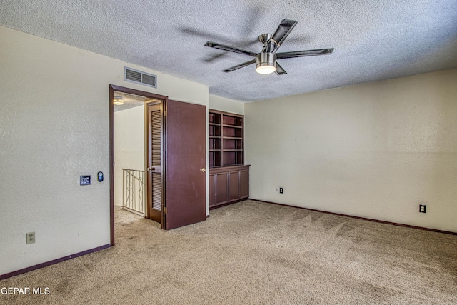 unfurnished bedroom with light carpet, baseboards, visible vents, a textured wall, and a textured ceiling