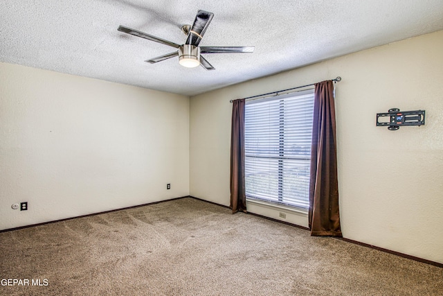 empty room with light carpet, ceiling fan, a textured ceiling, and baseboards