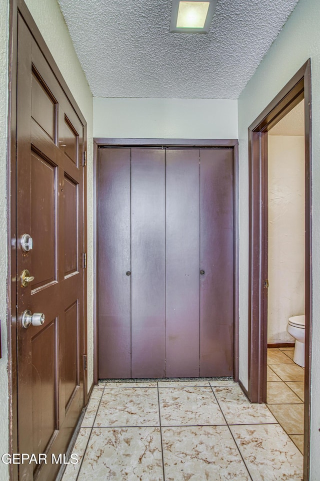 corridor featuring light tile patterned floors and a textured ceiling