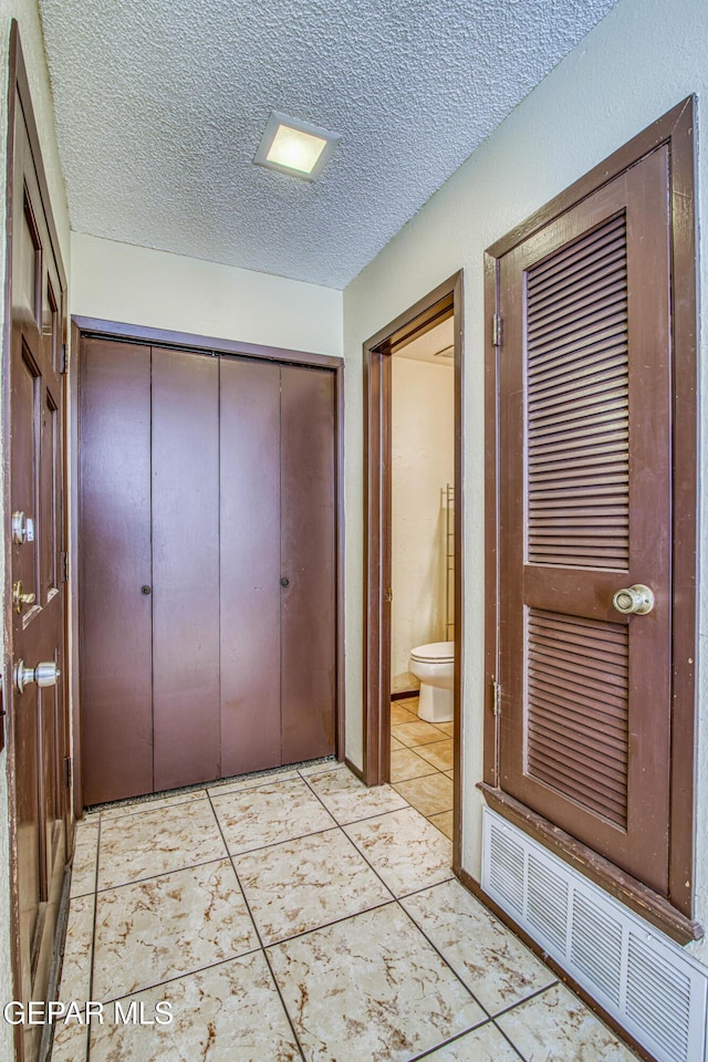 interior space featuring a textured ceiling, light tile patterned floors, and visible vents