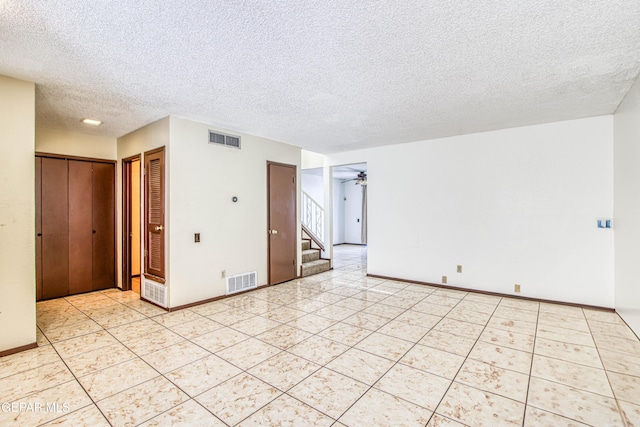 empty room with stairway, ceiling fan, light tile patterned floors, and visible vents