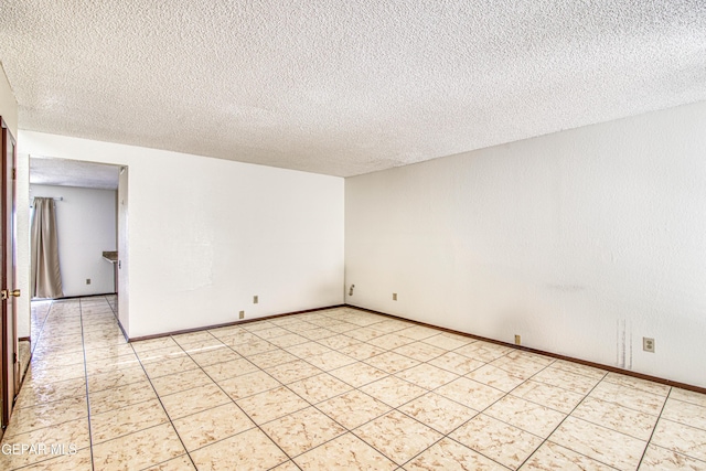 spare room featuring a textured ceiling and baseboards