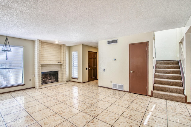 unfurnished living room with light tile patterned floors, a brick fireplace, visible vents, and stairs