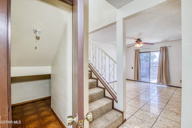 stairs with baseboards, a ceiling fan, and a textured ceiling