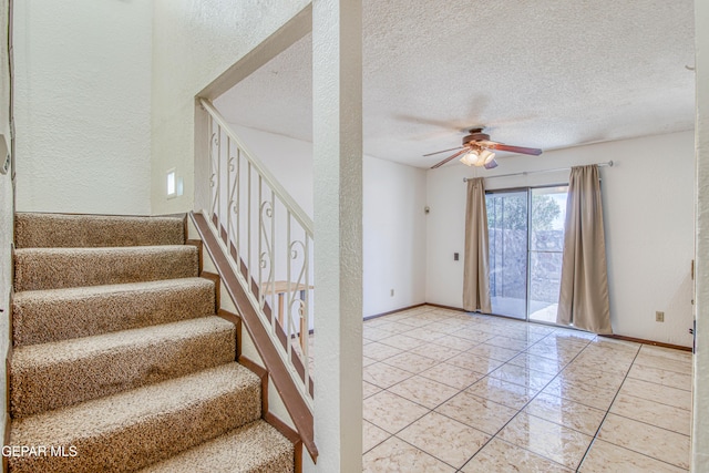 staircase with ceiling fan, baseboards, a textured ceiling, and a textured wall