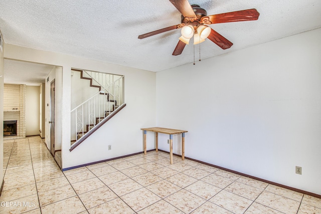 spare room with a textured ceiling, light tile patterned floors, a fireplace, baseboards, and stairway