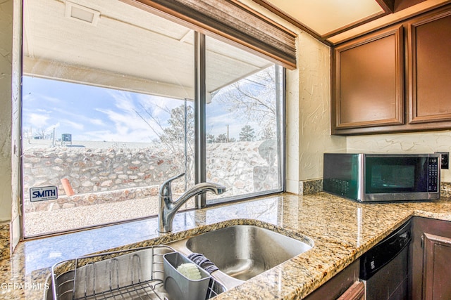 kitchen featuring light stone counters, a sink, brown cabinetry, dishwasher, and stainless steel microwave