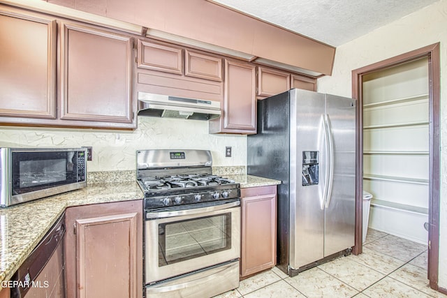 kitchen featuring a textured ceiling, stainless steel appliances, light stone counters, and under cabinet range hood