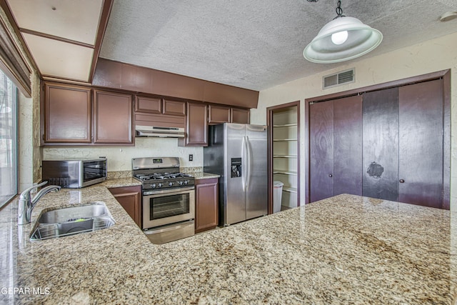 kitchen featuring under cabinet range hood, a sink, visible vents, hanging light fixtures, and appliances with stainless steel finishes