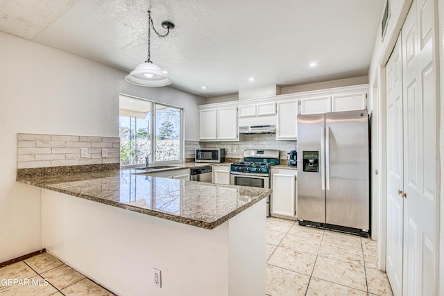 kitchen featuring tasteful backsplash, a peninsula, appliances with stainless steel finishes, and a sink