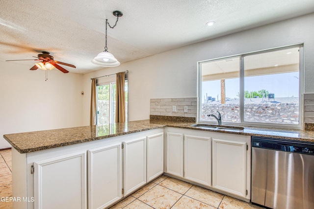 kitchen featuring a peninsula, decorative backsplash, dishwasher, a sink, and a textured ceiling