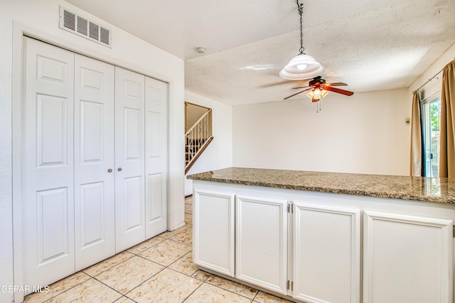 kitchen with light tile patterned floors, a ceiling fan, visible vents, decorative light fixtures, and white cabinetry