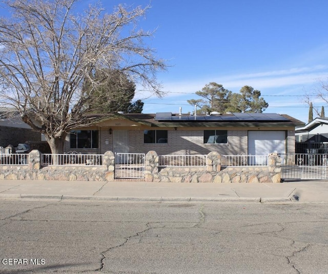 ranch-style house with a garage, a fenced front yard, and solar panels