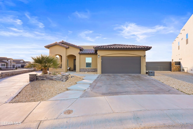 mediterranean / spanish house with stucco siding, fence, a garage, driveway, and a tiled roof