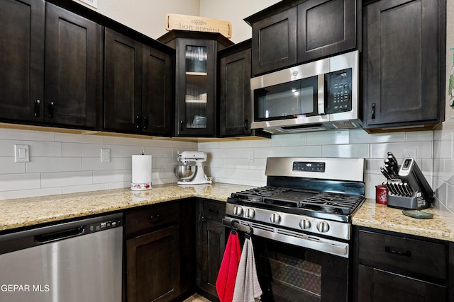 kitchen featuring dark brown cabinets, glass insert cabinets, stainless steel appliances, and backsplash