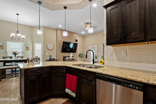 kitchen featuring light stone counters, pendant lighting, stainless steel dishwasher, a sink, and dark brown cabinets