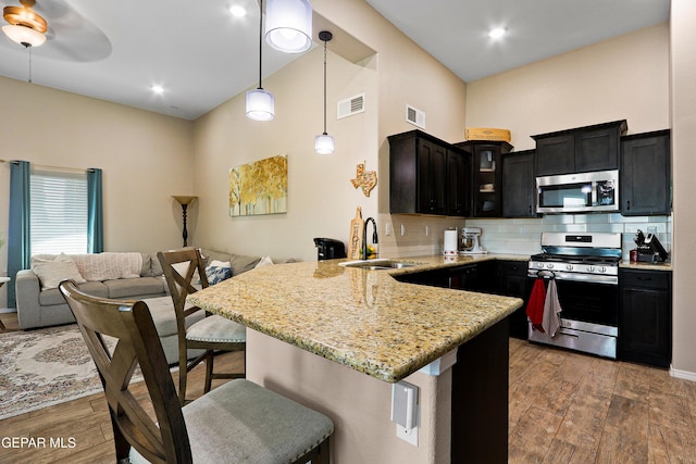 kitchen featuring glass insert cabinets, visible vents, a peninsula, and appliances with stainless steel finishes