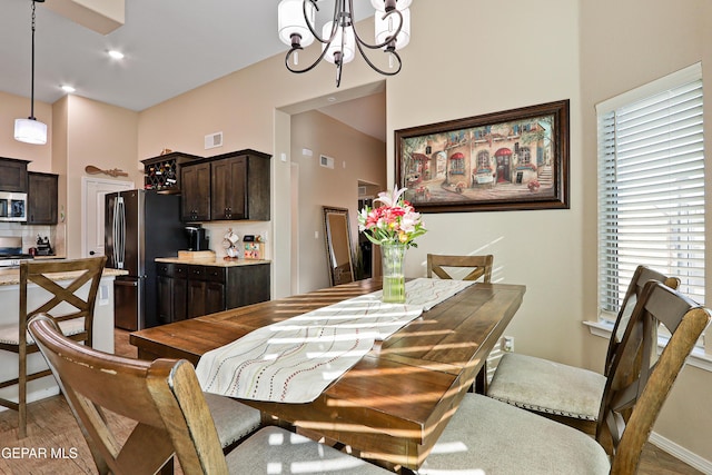 dining area with baseboards, wood finished floors, visible vents, and a notable chandelier