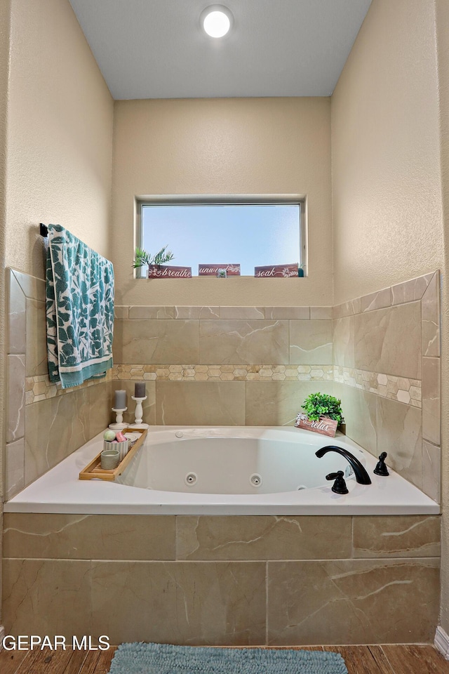 bathroom with a jetted tub, plenty of natural light, and wood finished floors