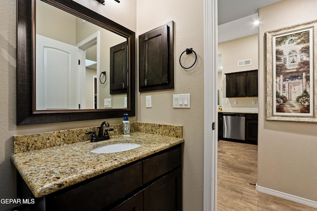 bathroom featuring baseboards, visible vents, decorative backsplash, wood finished floors, and vanity