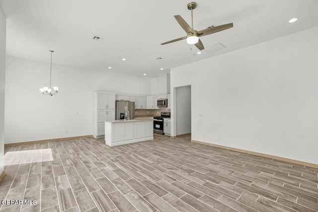 kitchen featuring white cabinets, open floor plan, a center island, stainless steel appliances, and light countertops