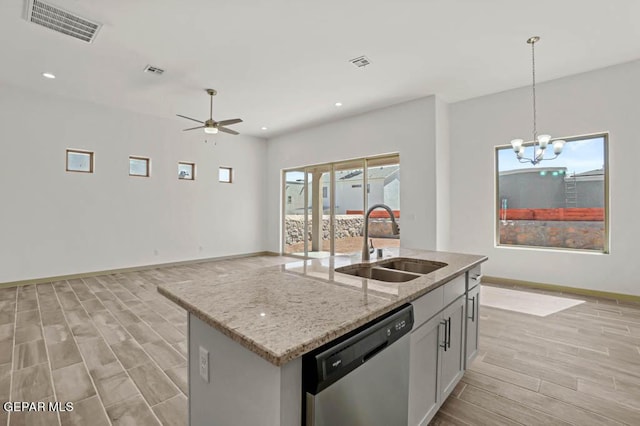 kitchen featuring visible vents, light stone counters, a kitchen island with sink, stainless steel dishwasher, and a sink