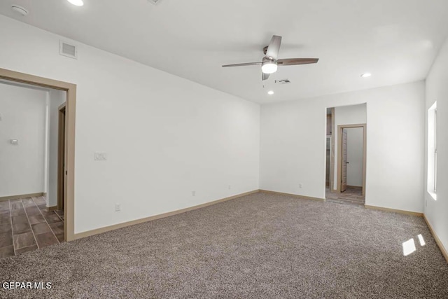 spare room with visible vents, dark carpet, and baseboards