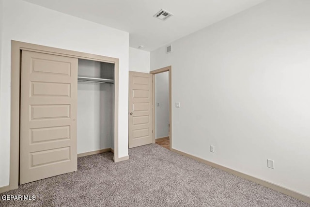 unfurnished bedroom featuring baseboards, a closet, visible vents, and light colored carpet