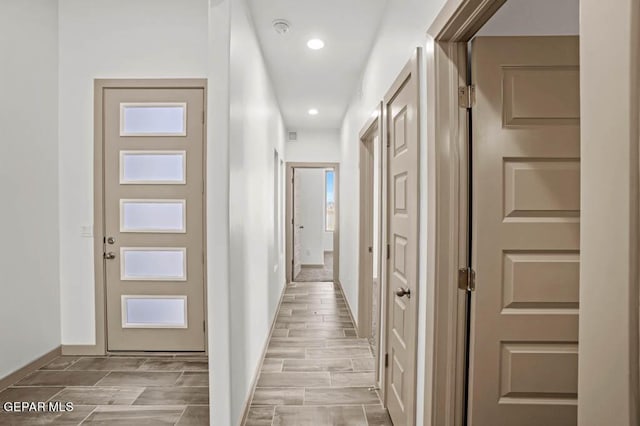 hall with wood tiled floor, baseboards, and recessed lighting