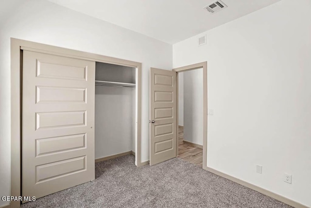 unfurnished bedroom with baseboards, a closet, visible vents, and light colored carpet