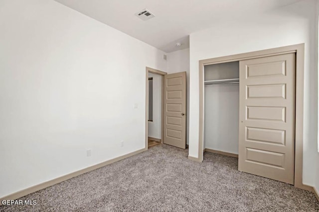 unfurnished bedroom featuring baseboards, a closet, visible vents, and light colored carpet