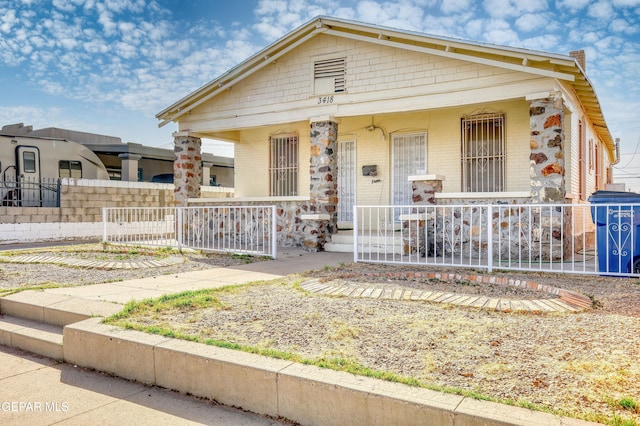 view of front of home with fence, a porch, and brick siding