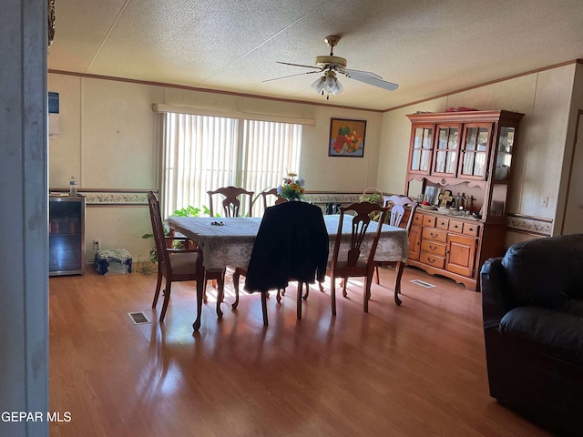 770 Eagles Den Ln, El Paso, TX 79927 - dining room featuring a textured ceiling, wine cooler, crown molding, and wood finished floors