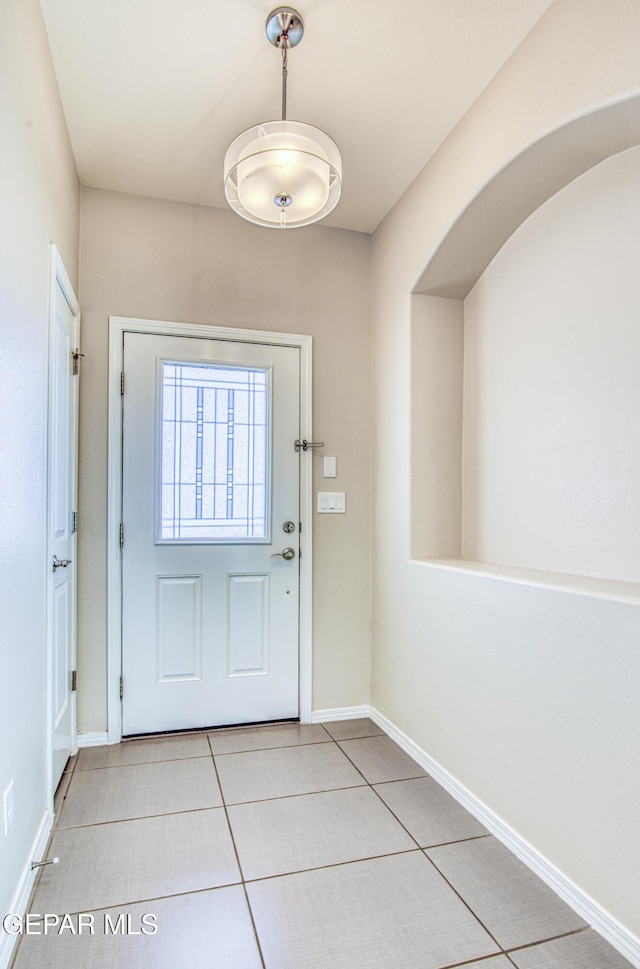 doorway with baseboards and light tile patterned floors