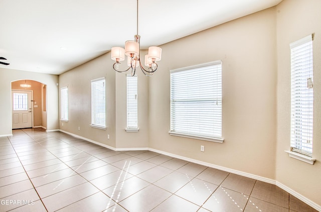 tiled empty room with arched walkways, baseboards, and an inviting chandelier