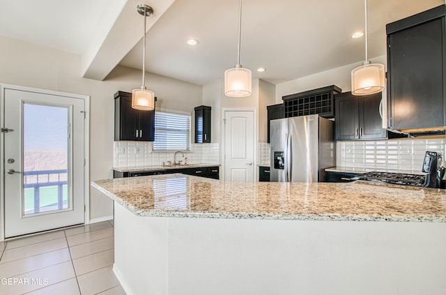 kitchen with a peninsula, stainless steel refrigerator with ice dispenser, a sink, and light stone countertops