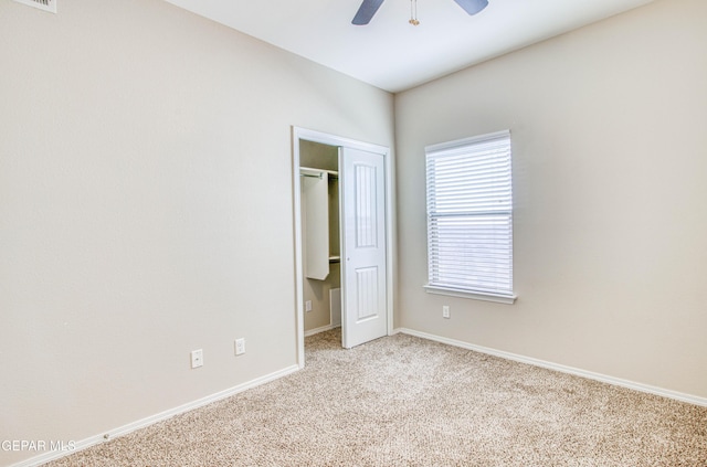 unfurnished bedroom with light carpet, visible vents, a ceiling fan, baseboards, and a closet