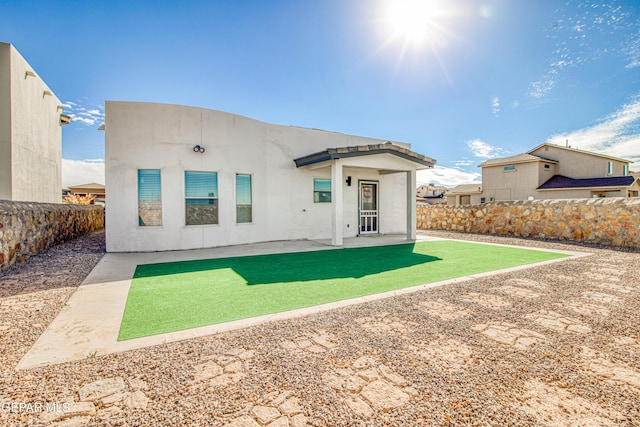 rear view of house with stucco siding, a fenced backyard, and a patio