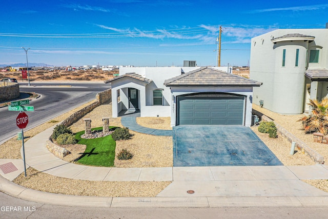 view of front of home with a garage, a tiled roof, driveway, and stucco siding