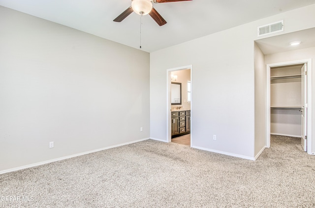 unfurnished bedroom featuring light carpet, baseboards, visible vents, a walk in closet, and a closet