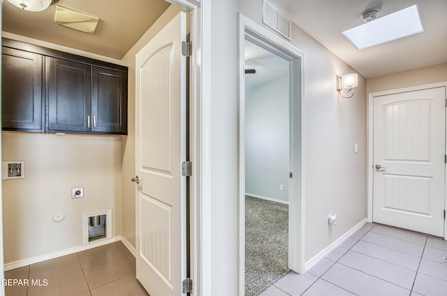 laundry area with cabinet space, light tile patterned floors, a skylight, and hookup for an electric dryer