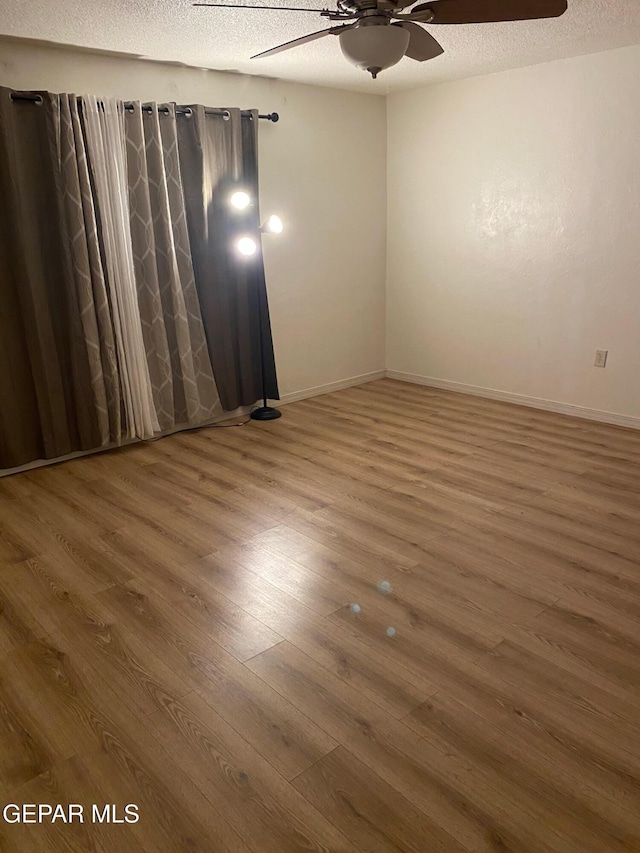 unfurnished room featuring a textured ceiling, wood finished floors, and a ceiling fan