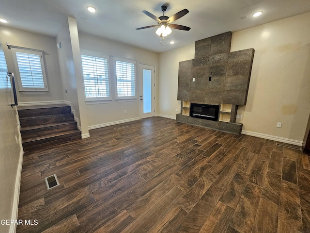 unfurnished living room with a ceiling fan, a fireplace, visible vents, and wood finished floors