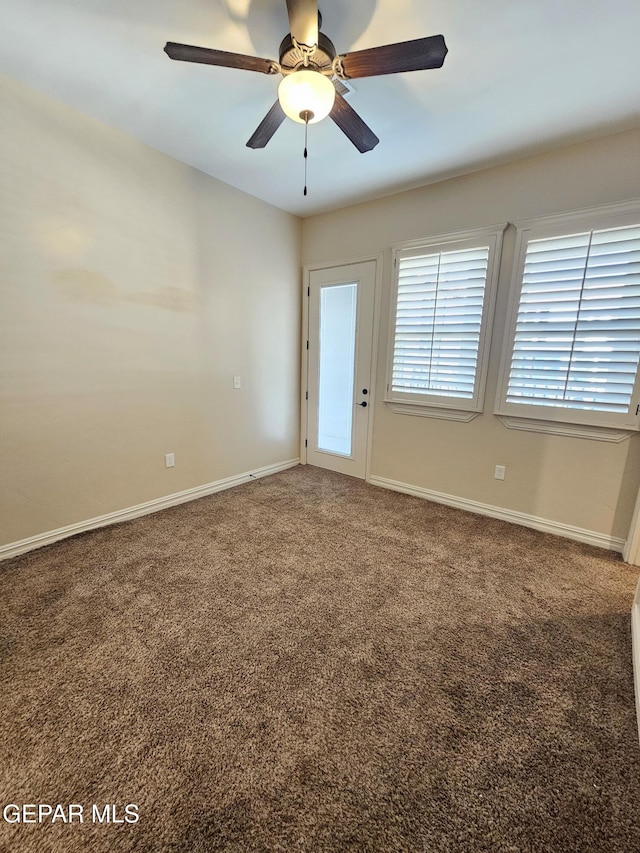 carpeted spare room featuring a ceiling fan and baseboards