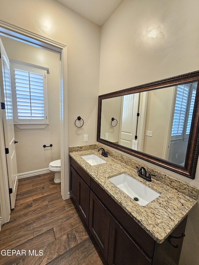 bathroom with wood finished floors, a sink, toilet, and baseboards