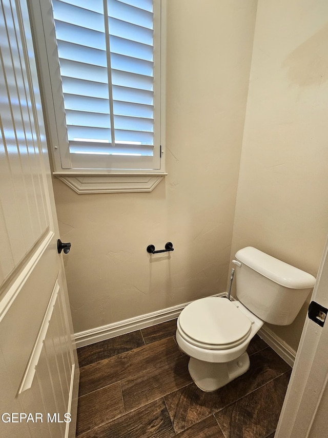 bathroom with wood finished floors, toilet, and baseboards