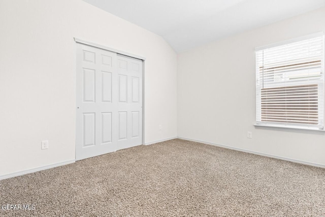 unfurnished bedroom with carpet floors, baseboards, vaulted ceiling, and a closet