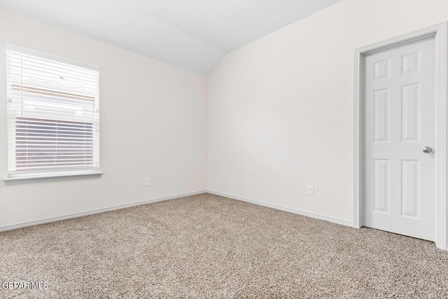 empty room with lofted ceiling, baseboards, and carpet