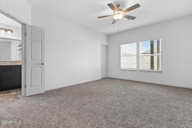 interior space with a sink, a ceiling fan, baseboards, and carpet flooring