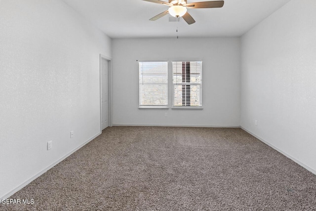 carpeted spare room featuring a ceiling fan and baseboards